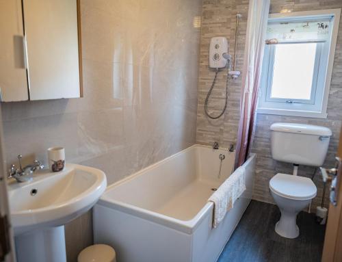 ein Badezimmer mit Badewanne, Toilette und Waschbecken in der Unterkunft Luxury North Coast 500 Cottage by Helmsdale, stunning sea views in Portgower