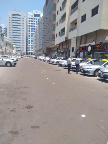 Dos hombres están parados al costado de una calle con autos. en Naimz short stay Apartment, en Abu Dabi