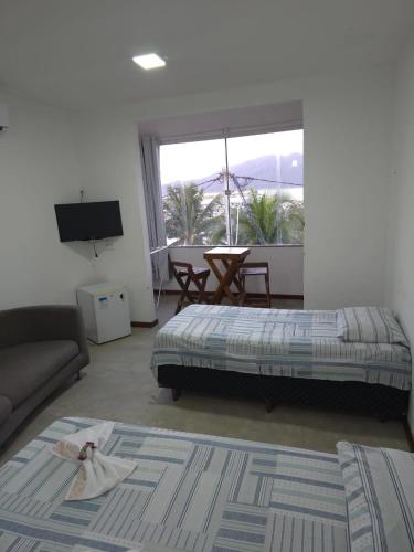 a living room with a bed and a couch at Pousada Pé Na Areia in Arraial do Cabo