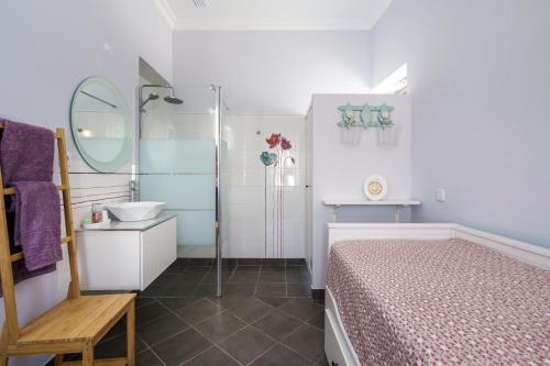 a bathroom with a bed and a sink and a mirror at Casa D'Nossa, casa tradicional e Moderna, vista 360º, piscina de agua salgada in Luz de Tavira