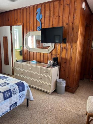 a bedroom with a dresser with a tv on a wall at Seahorse Inn in New Smyrna Beach