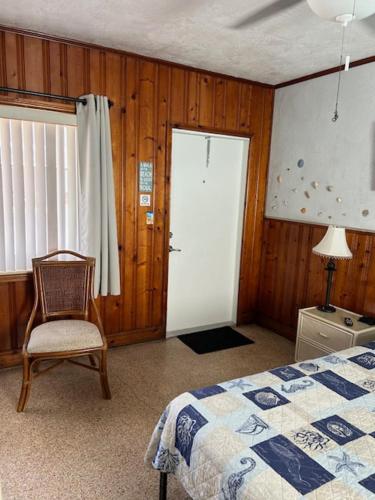 a bedroom with a bed and a chair and a door at Seahorse Inn in New Smyrna Beach
