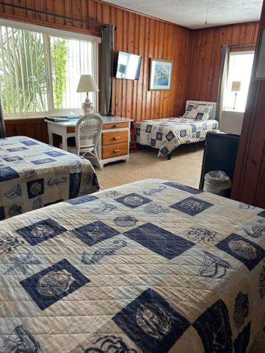 a hotel room with two beds and a desk and a bed at Seahorse Inn in New Smyrna Beach