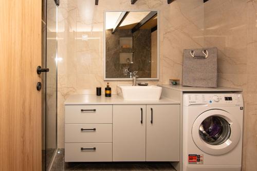 a bathroom with a sink and a washing machine at Rikanthos Stone Sea View Apartment ΙΙ in Kissamos