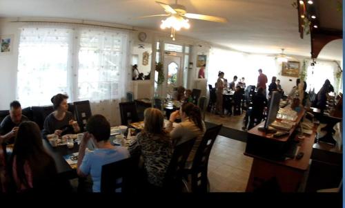 a group of people sitting at tables in a restaurant at Olympos Panzió in Budaörs