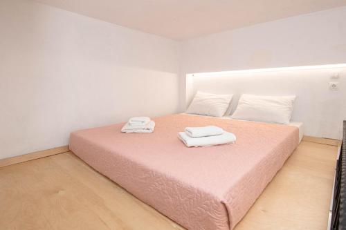 a bedroom with a pink bed with two towels on it at Rikanthos Stone Sea View Apartment ΙΙ in Kissamos
