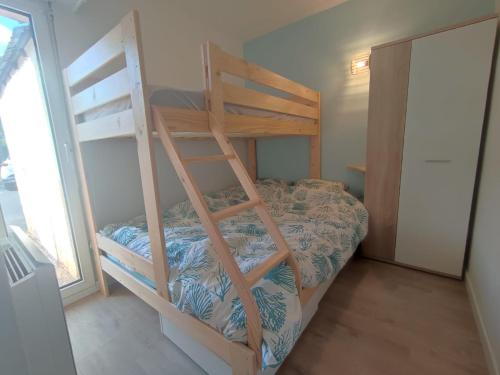 a bedroom with a bunk bed with a ladder at Charmant appartement T2 - Proposition de séjours avec des activités locales - 200m de la plage avec jardin et terrasse- RDC in Carnac
