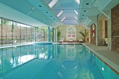 an indoor swimming pool with a large ceiling at Rushton Hall Hotel and Spa in Kettering