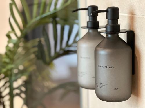two bottles of soap sitting next to a plant at TRULY - Viel Platz für Business & Familie - Modern, Garage, Fahrstuhl in Augsburg