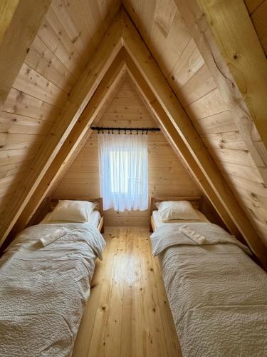 two beds in a wooden attic with a window at Mountain Houses Šarović in Žabljak