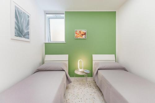 two beds in a room with green walls at Ciraccio Apartments in Procida