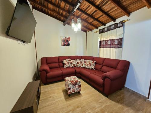 a living room with a red couch and a flat screen tv at Hotel Finca Recreacional La Fortaleza 
