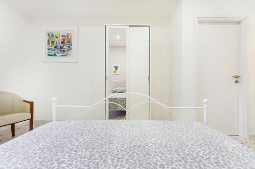 a white bedroom with a bed and a mirror at Ciraccio Apartments in Procida