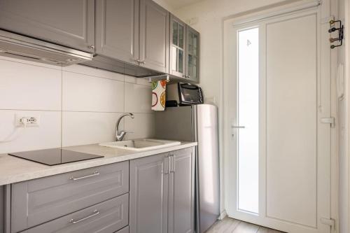 La cuisine blanche est équipée d'un évier et d'un réfrigérateur. dans l'établissement Cosy apartment near the Lake, à Riva del Garda