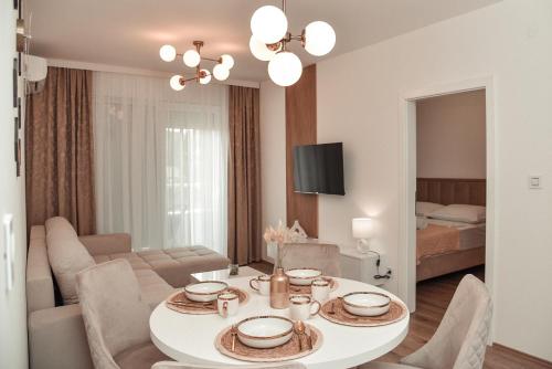 a dining room and living room with a table and chairs at S&L luxury apartman in Banja Koviljača