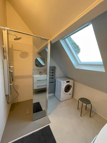 une petite salle de bains avec une fenêtre et un lave-linge. dans l'établissement le gite de la pommeraie, à Le Bois-Robert