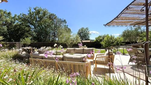 un patio avec des canapés et des chaises dans un jardin dans l'établissement Villa Céladon Valbonne - Piscine, à Valbonne