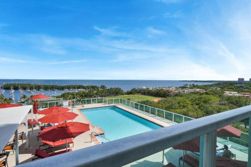 a balcony with a swimming pool and red umbrellas at Astonishing SEA VIEW Studio in Grove in Miami