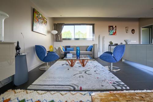 un salon avec des chaises bleues et un canapé dans l'établissement Sérénité au fil de l'eau Appartement de standing, à LʼIsle-sur-la-Sorgue