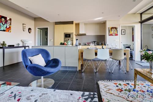 un salon avec une chaise bleue et une cuisine dans l'établissement Sérénité au fil de l'eau Appartement de standing, à LʼIsle-sur-la-Sorgue