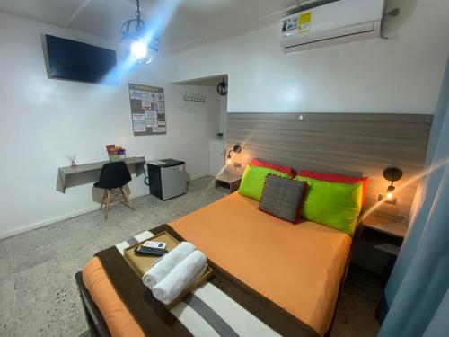 Un dormitorio con una cama grande con almohadas verdes y rojas en Hotel Tamaiti, en Ríohacha