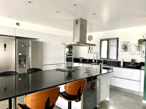 une cuisine avec un comptoir noir et des chaises en bois dans l'établissement Villa DIANE, à Boran-sur-Oise