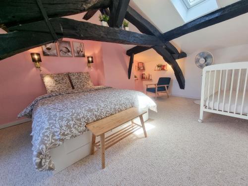 Un dormitorio con paredes rosas y una cama y una cuna. en Duplex Le Chai de l'Abreuvoir, en Saintes