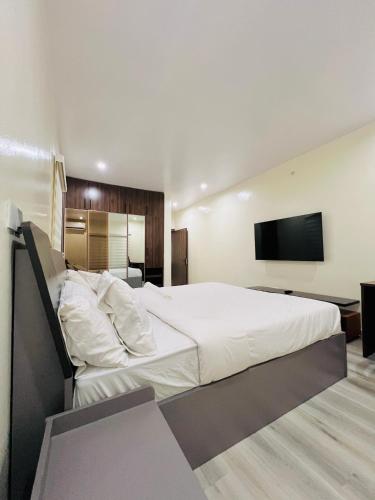 Un dormitorio con una gran cama blanca y un televisor de pantalla plana. en Elegant Living, en Lekki