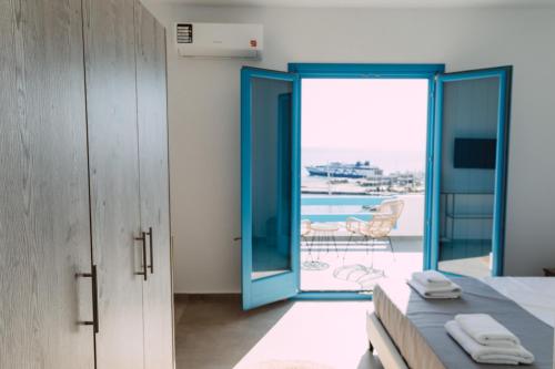 a bedroom with blue doors and a view of the ocean at Amuse Mykonos Boutique Hotel in Mýkonos City