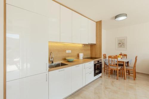a kitchen with white cabinets and a dining table at Bella Vista Luxure Apartments in Baošići