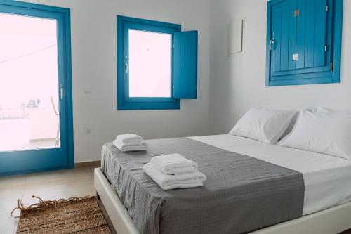 a bedroom with blue windows and a bed with towels at Amuse Mykonos Boutique Hotel in Mýkonos City