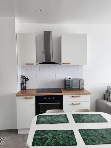 une cuisine avec des armoires blanches et un four à plaques de cuisson dans l'établissement Appartement Fleur De Houblon, à Schiltigheim