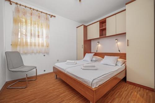 a bedroom with a bed and a chair in it at Apartment Bellistra Rabac in Rabac