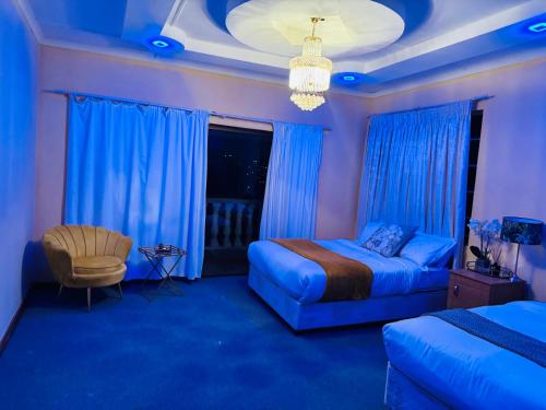 GoldenWays Motel في مبابان: غرفة نوم بسرير وكرسي واضاءات زرقاء