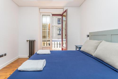 レオンにあるBaruHaus Santo Domingoの青いベッドと2枚のタオルが置かれた寝室