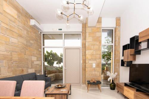 a living room with a stone wall and a chandelier at Rikanthos Stone Sea View Apartment ΙΙ in Kissamos