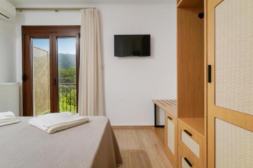 a bedroom with a bed and a television and a window at Avli 1976 in Panayia