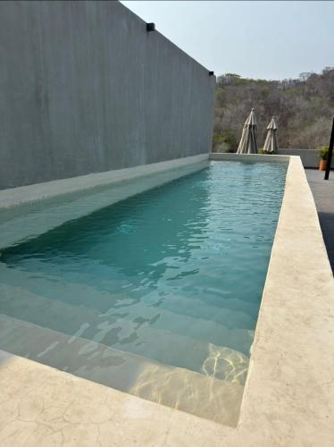 a swimming pool with blue water next to a wall at Nabani Condominios T3 in Santa Cruz Huatulco