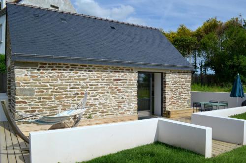a brick building with a deck and a patio at La petite maison de Celestine in Plonéour-Lanvern