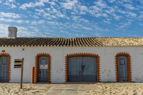 a white building with three garage doors in front at Casa D'Nossa, casa tradicional e Moderna, vista 360º, piscina de agua salgada in Luz de Tavira