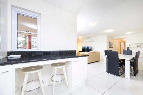 a kitchen and dining room with a table and stools at Sunrise 702 in Tuncurry