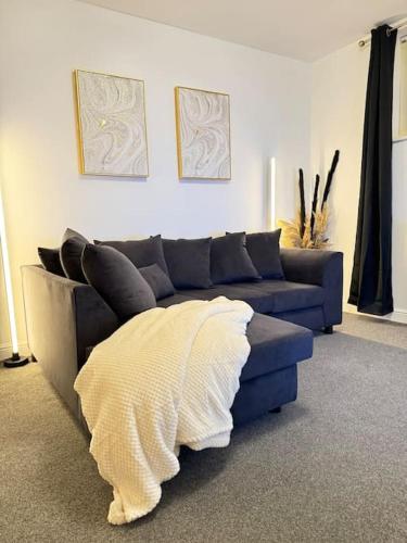 a living room with a blue couch with a white blanket at Luxury cozy 3 bed Apartment 5mins from city - free parking! in Nottingham