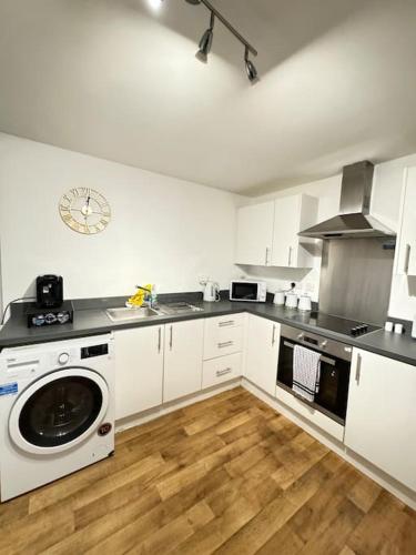 a kitchen with white cabinets and a washer in it at Luxury cozy 3 bed Apartment 5mins from city - free parking! in Nottingham