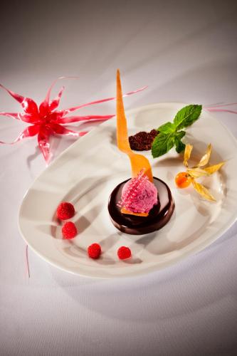 a dessert on a white plate with berries on it at Le Bois Dormant-Hôtel Restaurant & Spa Logis Hôtel in Champagnole