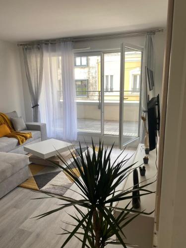 un salon avec un canapé et une plante en pot dans l'établissement Appartement 24h du Mans, au Mans