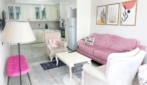 Midyat的住宿－Midyat Merkezde Lüks Daire，客厅配有粉红色的沙发和两把椅子