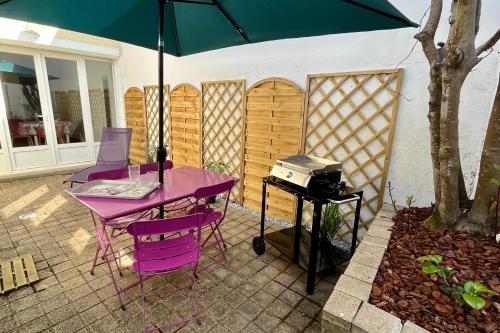 une table et des chaises violettes avec un parasol sur la terrasse dans l'établissement Maison 