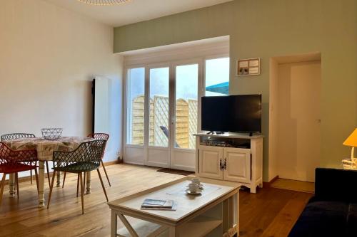 un salon avec une télévision et une table avec des chaises dans l'établissement Maison 