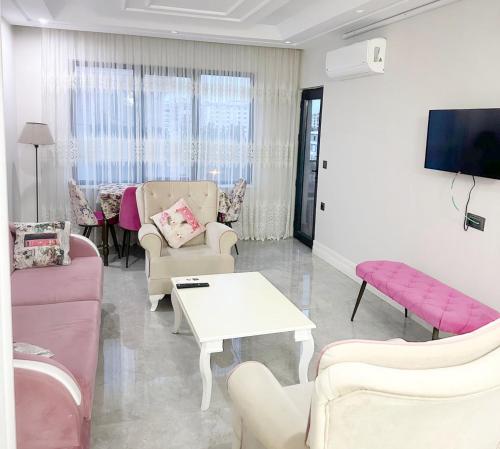 a living room with pink furniture and a tv at Midyat Merkezde Lüks Daire in Midyat