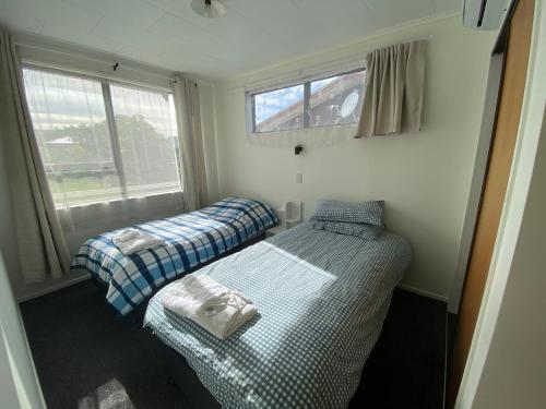 two beds in a small room with a window at Aberdeen home stay in Gisborne